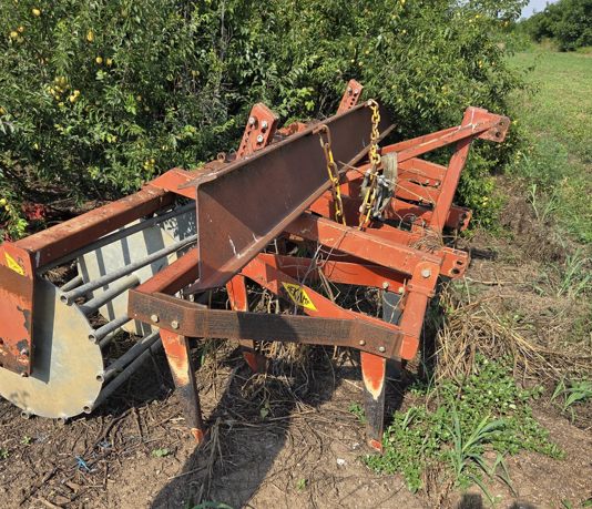 Orange scarifier standing beside a field